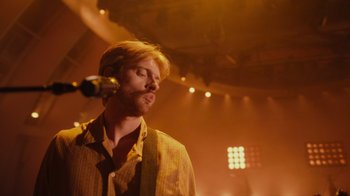 Movie still from “Happier Than Ever: A Love Letter to Los Angeles” (2021), directed by Patrick Osborne – A man with a beard is singing into a microphone; Close Up shot, Over the shoulder angle