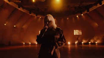 Movie still from “Happier Than Ever: A Love Letter to Los Angeles” (2021), directed by Patrick Osborne – A woman is singing into a microphone on a stage; Wide shot, Low angle