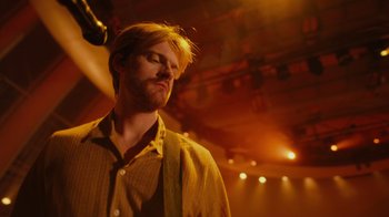 Movie still from “Happier Than Ever: A Love Letter to Los Angeles” (2021), directed by Patrick Osborne – A man with his eyes closed in a dark room; Close Up shot, Low angle