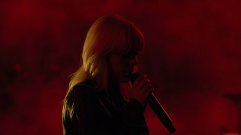Movie still from “Happier Than Ever: A Love Letter to Los Angeles” (2021), directed by Patrick Osborne – A woman with blonde hair is holding a microphone in her hand; Medium shot, Low angle