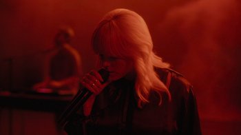 Movie still from “Happier Than Ever: A Love Letter to Los Angeles” (2021), directed by Patrick Osborne – A woman with blonde hair is singing into a microphone; Medium shot, High angle