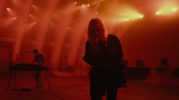 Movie still from “Happier Than Ever: A Love Letter to Los Angeles” (2021), directed by Patrick Osborne – A woman standing on a stage holding a microphone; Wide shot, Low angle