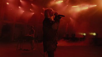 Movie still from “Happier Than Ever: A Love Letter to Los Angeles” (2021), directed by Patrick Osborne – A woman singing into a microphone on a stage; Wide shot, Low angle