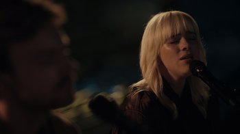 Movie still from “Happier Than Ever: A Love Letter to Los Angeles” (2021), directed by Patrick Osborne – A woman with blonde hair is holding a microphone; Close Up shot, Over the shoulder angle