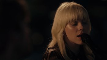 Movie still from “Happier Than Ever: A Love Letter to Los Angeles” (2021), directed by Patrick Osborne – A woman with long blonde hair is singing into a microphone; Close Up shot, Over the shoulder angle