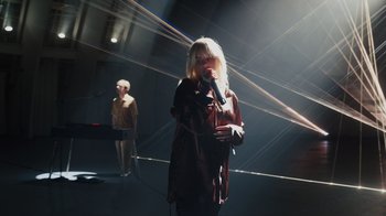 Movie still from “Happier Than Ever: A Love Letter to Los Angeles” (2021), directed by Patrick Osborne – A woman is holding a microphone in her hand; Wide shot, Low angle