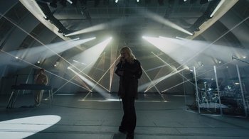 Movie still from “Happier Than Ever: A Love Letter to Los Angeles” (2021), directed by Patrick Osborne – A woman standing in front of a stage with lights; Wide shot, Low angle