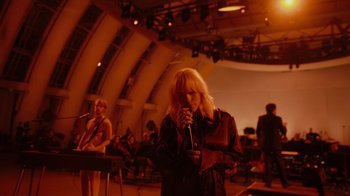 Movie still from “Happier Than Ever: A Love Letter to Los Angeles” (2021), directed by Patrick Osborne – A woman holding a microphone in front of a crowd; Wide shot, High angle