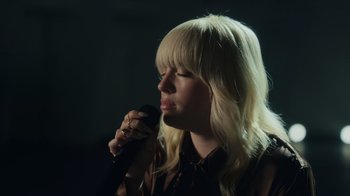 Movie still from “Happier Than Ever: A Love Letter to Los Angeles” (2021), directed by Patrick Osborne – A woman holding a microphone up to her face; Close Up shot, Low angle