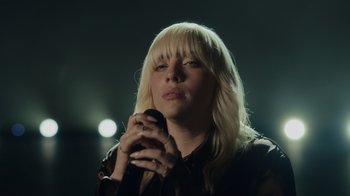 Movie still from “Happier Than Ever: A Love Letter to Los Angeles” (2021), directed by Patrick Osborne – A woman holding a cell phone up to her face; Close Up shot, Low angle
