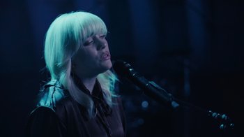 Movie still from “Happier Than Ever: A Love Letter to Los Angeles” (2021), directed by Patrick Osborne – A woman with blonde hair is singing into a microphone; Close Up shot, High angle