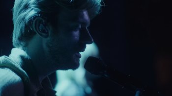Movie still from “Happier Than Ever: A Love Letter to Los Angeles” (2021), directed by Patrick Osborne – A person holding a microphone; Close Up shot, Over the shoulder angle