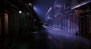 Movie still from “Hard Target” (1993), directed by John Woo – A street with a car parked on the side of the road; Extreme Wide shot, High angle