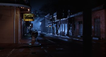 Movie still from “Hard Target” (1993), directed by John Woo – A city street at night lit by street lights; Extreme Wide shot, High angle