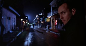 Movie still from “Hard Target” (1993), directed by John Woo – A man standing on the side of a street at night; Close Up shot, Low angle