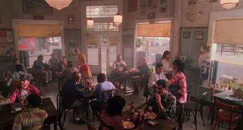 Movie still from “Hard Target” (1993), directed by John Woo – A group of people sitting at tables eating food; Wide shot, High angle