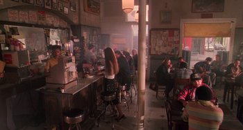 Movie still from “Hard Target” (1993), directed by John Woo – A group of people sitting at a bar in a restaurant; Wide shot, High angle