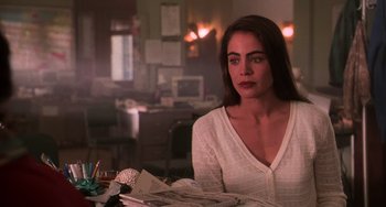 Movie still from “Hard Target” (1993), directed by John Woo – A woman sitting at a table in front of papers; Close Up shot, Over the shoulder angle