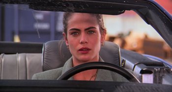 Movie still from “Hard Target” (1993), directed by John Woo – A woman sitting in the driver's seat of a car; Close Up shot, Over the shoulder angle