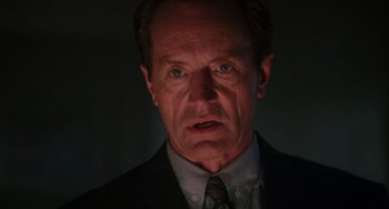 Movie still from “Hard Target” (1993), directed by John Woo – A person wearing a suit and tie; Close Up shot, Low angle