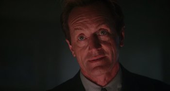 Movie still from “Hard Target” (1993), directed by John Woo – A person wearing a suit and tie; Close Up shot, Low angle