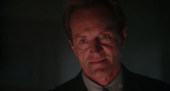 Movie still from “Hard Target” (1993), directed by John Woo – A person wearing a suit and tie; Close Up shot, Low angle