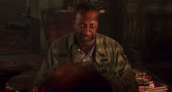 Movie still from “Hard Target” (1993), directed by John Woo – A person wearing a military uniform; Close Up shot, Over the shoulder angle