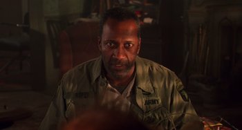 Movie still from “Hard Target” (1993), directed by John Woo – A person sitting in a chair; Close Up shot, Over the shoulder angle