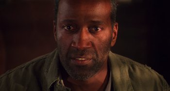 Movie still from “Hard Target” (1993), directed by John Woo – A man's face in a dimly - lit room; Close Up shot, Low angle