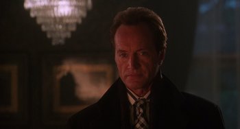 Movie still from “Hard Target” (1993), directed by John Woo – A person wearing a suit and tie; Close Up shot, Low angle