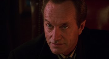 Movie still from “Hard Target” (1993), directed by John Woo – A person wearing a suit and tie; Close Up shot, Low angle