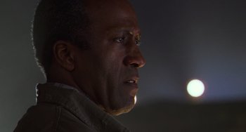 Movie still from “Hard Target” (1993), directed by John Woo – A man's face in the dark; Close Up shot, Low angle