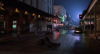 Movie still from “Hard Target” (1993), directed by John Woo – A person laying on the ground in the middle of the street; Extreme Wide shot, High angle