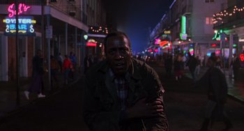 Movie still from “Hard Target” (1993), directed by John Woo – A black man is standing in the middle of the street; Medium shot, Low angle