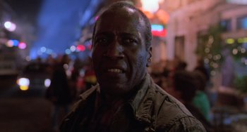 Movie still from “Hard Target” (1993), directed by John Woo – A man's face in the dark; Close Up shot, Low angle