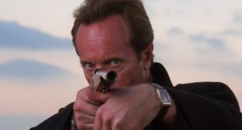 Movie still from “Hard Target” (1993), directed by John Woo – A person holding a gun; Close Up shot, Low angle