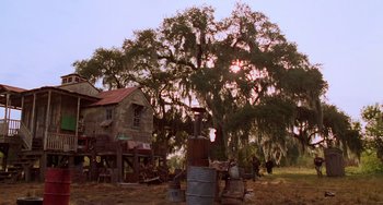 Movie still from “Hard Target” (1993), directed by John Woo – An old house with a tree in front of it; Extreme Wide shot, Low angle