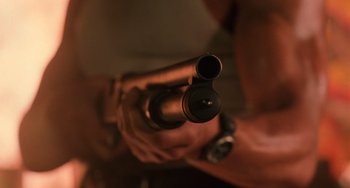 Movie still from “Hard Target” (1993), directed by John Woo – A person holding a gun in their hands; Extreme Close Up shot, Low angle