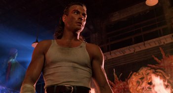 Movie still from “Hard Target” (1993), directed by John Woo – A person with long hair wearing a tank top; Close Up shot, Low angle