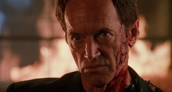 Movie still from “Hard Target” (1993), directed by John Woo – A person with blood on his face; Close Up shot, Over the shoulder angle