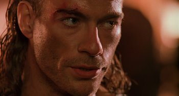 Movie still from “Hard Target” (1993), directed by John Woo – A man's face with blood on his face; Close Up shot, Over the shoulder angle