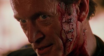 Movie still from “Hard Target” (1993), directed by John Woo – A person with blood on his face; Close Up shot, Low angle