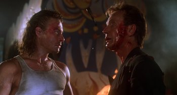Movie still from “Hard Target” (1993), directed by John Woo – A man with blood on his face and another man with blood on his face; Close Up shot, Over the shoulder angle