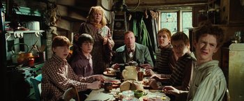 Movie still from “Harry Potter and the Chamber of Secrets” (2002), directed by Chris Columbus – A group of people sitting at a table with plates of food; Medium shot, High angle