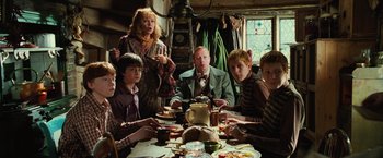 Movie still from “Harry Potter and the Chamber of Secrets” (2002), directed by Chris Columbus – A group of people sitting at a table with plates of food; Medium shot, High angle