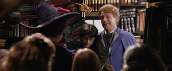 Movie still from “Harry Potter and the Chamber of Secrets” (2002), directed by Chris Columbus – A man and a woman standing next to each other in a library; Medium shot, Over the shoulder angle