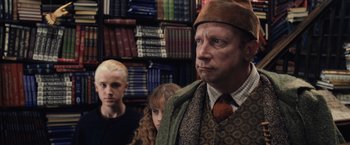 Movie still from “Harry Potter and the Chamber of Secrets” (2002), directed by Chris Columbus – A man and two women standing in front of a book shelf; Close Up shot, Over the shoulder angle