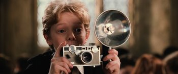 Movie still from “Harry Potter and the Chamber of Secrets” (2002), directed by Chris Columbus – A young boy holding a camera in front of his face; Close Up shot, Low angle