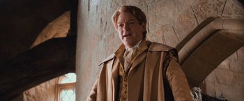 Movie still from “Harry Potter and the Chamber of Secrets” (2002), directed by Chris Columbus – A man in a brown coat standing in front of a wall; Medium shot, Low angle