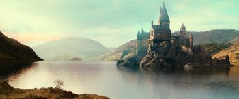 Movie still from “Harry Potter and the Chamber of Secrets” (2002), directed by Chris Columbus – A castle sits on top of a hill near a body of water; Extreme Wide shot, High angle